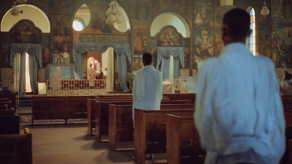 Homem em pé diante de banco de igreja